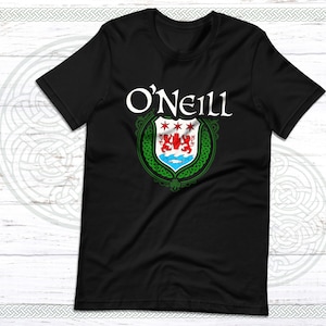 May include: Black t-shirt featuring the name "O'Neill" in white script above a detailed crest. The crest includes red lions, blue water, and green Celtic knotwork, all set against a white background.