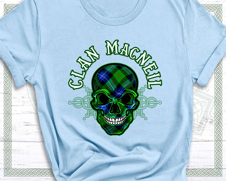 May include: A light blue t-shirt with a green and blue skull design. The skull is wearing a tartan pattern. The text "Clan MacNeil" is written in a green and white font above the skull.