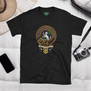 Könnte beinhalten: Schwarzes T-Shirt mit einem goldenen und grünen Wappen, das einen weißen Hund und den Text "DEO JUVANTE INVIDIAM SUPERABO MACTHOMAS" zeigt.