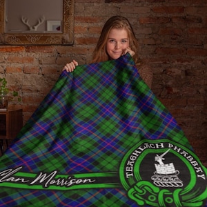 May include: A green, blue, and red tartan blanket with a white crest and the text "Clan Morrison" and "Teachlach Phabaay".