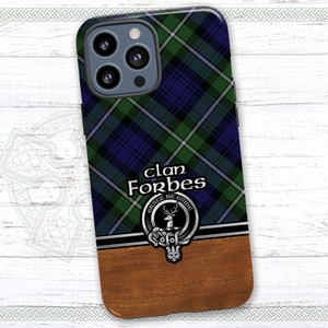 May include: A phone case with a blue, green, and white plaid pattern. The case has a wood-grain bottom and a silver crest with the text "Clan Forbes, Grace Me Guide".