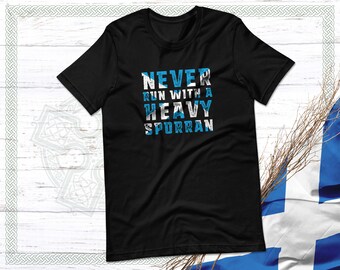 Puede incluir: Camiseta negra con un gráfico blanco desgastado que dice "NEVER RUN WITH A HEAVY SPORRAN". El gráfico está superpuesto con un patrón de cuadros azul y blanco.