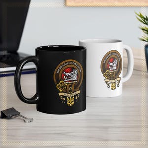 May include: Two ceramic coffee mugs with a black and white design. The design features a wolf's head with a red and black tartan pattern and the text "Hunguam Obliviscar Maciver".