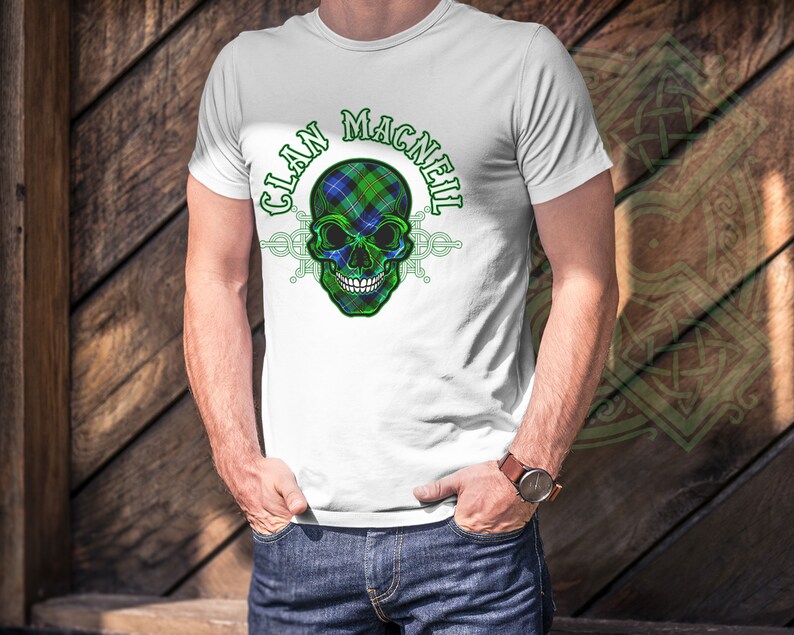 May include: White t-shirt with a green, blue, and white skull graphic and the text "Clan MacNeil" printed on the front.