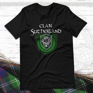 May include: Black t-shirt featuring a green and blue clan crest with the text "Clan Sutherland" in white.