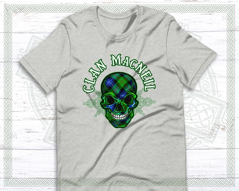 May include: Gray t-shirt with a green, blue, and black skull design. The skull is wearing a tartan pattern and the text "Clan MacNeil" is written around the skull.