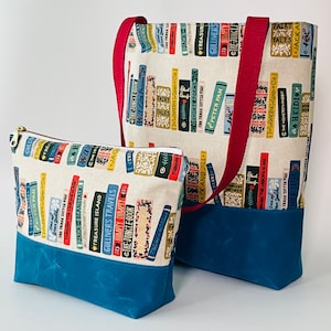 May include: Two fabric totes with a book print design. The larger tote has a red strap and a teal blue bottom. The smaller tote is a zippered pouch with a teal blue bottom.