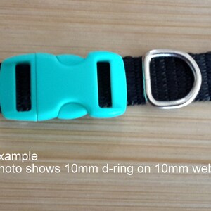 Op de afbeelding: Een zwarte nylon hondenriem met een turquoise plastic gesp en een zilveren D-ring. Voorbeeld: De foto toont een 10 mm D-ring op een 10 mm brede band.