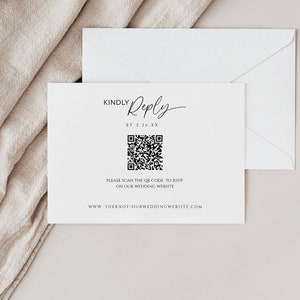以下が含まれることがあります： 白いRSVPカードに黒い文字で「KINDLY Reply BY 2.26.XX」と書かれています。テキストの下には白黒のQRコードがあります。QRコードの下のテキストは「PLEASE SCAN THE QR CODE TO RSVP ON OUR WEDDING WEBSITE WWW.THEKNOT/OURWEDDINGWEBSITE.COM」です