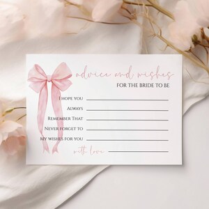 May include: A white card with the text "advice and wishes for the bride to be" and a pink bow illustration. The card has lines for writing and is decorated with pink flowers.
