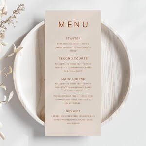 Könnte beinhalten: Eine beige Speisekarte mit braunem Rand und dem Wort "MENU" in brauner Schrift. Die Speisekarte listet folgende Gänge auf: Vorspeise, Zweiter Gang, Hauptgericht und Dessert. Jeder Gang wird beschrieben.
