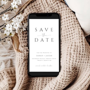 Puede incluir: Un teléfono inteligente negro con una pantalla blanca que muestra un anuncio de guardar la fecha para una boda. El texto dice "Save the Date" con la fecha "Saturday August Twenty Sixth, Twenty Twenty XX" y los nombres "Sarah + Jason".