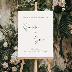 May include: White wedding welcome sign with black calligraphy text that reads "Welcome to the wedding of Sarah and Jason 08.26.20XX We're so glad you're here".