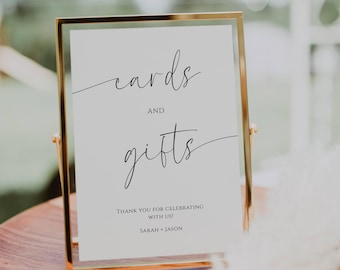 May include: A white sign in a gold frame with the text "cards and gifts" in black cursive font. The sign also includes the text "Thank you for celebrating with us! Sarah + Jason".