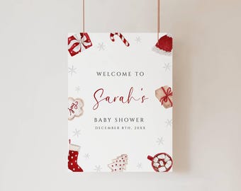 May include: A festive baby shower sign with watercolor illustrations of holiday-themed elements. The sign reads "Welcome to Sarah's Baby Shower, December 8th, 20XX." Decorations include snowflakes, gifts, and cookies.