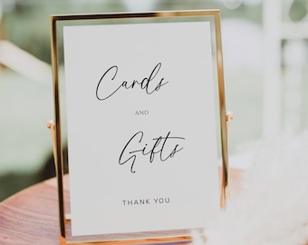 May include: A gold-framed sign with white background and black text that reads "Cards and Gifts Thank You".