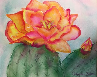 Puede incluir: Pintura a la acuarela de una vibrante flor de cactus naranja y rosa, sobre una almohadilla de cactus verde. La obra de arte presenta una representación detallada de los pétalos de la flor y un pequeño capullo. La firma del artista es visible.