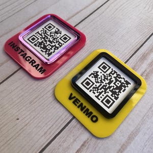 May include: Two QR code social media tags. One is pink with "INSTAGRAM" printed on it, and the other is yellow with "VENMO" printed on it. Both have a black and white QR code in the center.