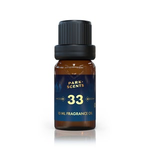 Puede incluir: Una pequeña botella de vidrio marrón con aceite de fragancia y tapa negra. La etiqueta azul oscuro tiene el texto dorado "PARK+ SCENTS 33" y "10 ML FRAGRANCE OIL". La botella contiene 10 ml de aceite.