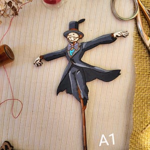 May include: A wooden cutout of a character from the movie Howl's Moving Castle. The character is wearing a black suit, a blue bow tie, and a top hat. The cutout is painted in shades of gray, blue, and black. The character is holding out its arms and has a friendly expression on its face. The cutout is labeled "A1".