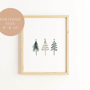 May include: A framed print featuring three stylized Christmas trees in dark green, with gold star accents. The artwork is on a white background, framed in natural wood. The finished size is 8 x 10 inches.