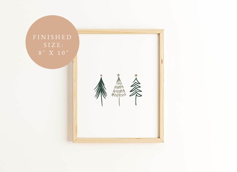 May include: A framed print featuring three stylized Christmas trees in dark green, with gold star accents. The artwork is on a white background, framed in natural wood. The finished size is 8 x 10 inches.