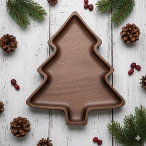 Op de afbeelding: Een bruine houten serveerschaal in de vorm van een kerstboom. De schaal is omgeven door dennenappels, dennentakken en rode bessen, allemaal gerangschikt op een wit houten oppervlak. Een feestelijk vakantiethema.