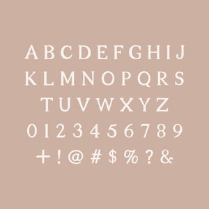 May include: White serif font alphabet, numbers, and symbols on a light brown background. The letters A through Z are displayed in three rows, followed by numbers 0 through 9, and then symbols including +, !, @, #, $, %, ?, and &.