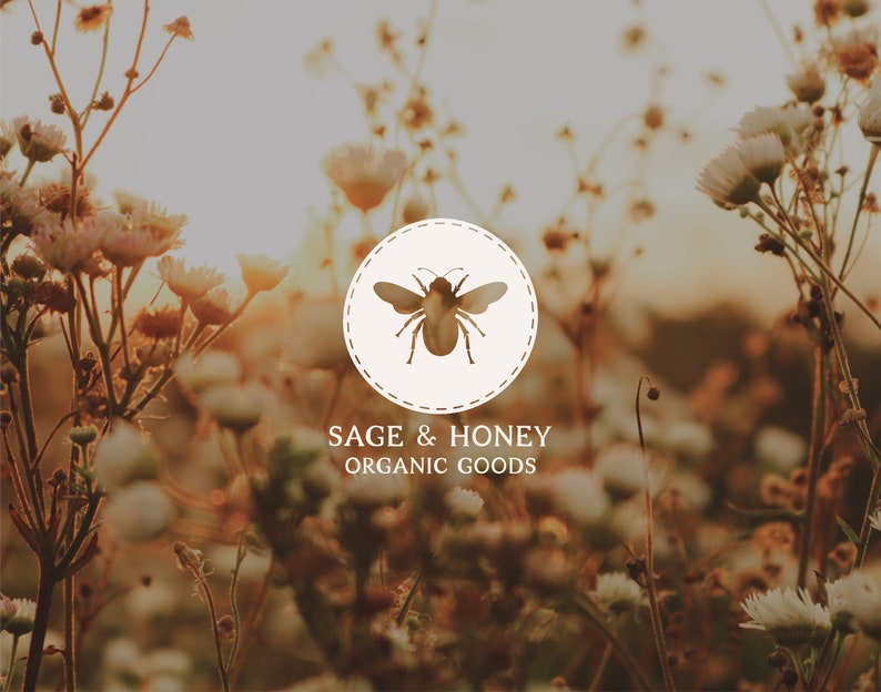 May include: A logo for "Sage & Honey Organic Goods" featuring a bee illustration inside a circular design. The logo is set against a blurred background of wildflowers in a field, with the text "Sage & Honey Organic Goods" below.