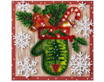 May include: A green mitten with a red cuff is filled with a gingerbread man, a candy cane, and a small Christmas tree. The mitten is surrounded by white snowflakes on a brown wooden background.