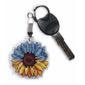 Pode incluir: Um chaveiro em forma de girassol com um design azul, amarelo e vermelho. O chaveiro está preso a um chaveiro prateado.