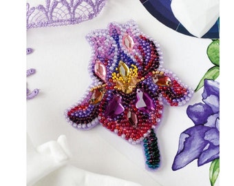 May include: A beaded flower brooch with purple, pink, red, and yellow beads. The brooch is shaped like an iris flower and has a green stem.