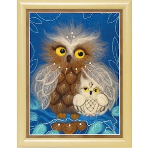 May include: A framed needle felted artwork featuring two owls on a blue background. The larger owl is brown with yellow eyes and white feathers. The smaller owl is white with yellow eyes. Both owls have a whimsical, cartoon-like appearance.
