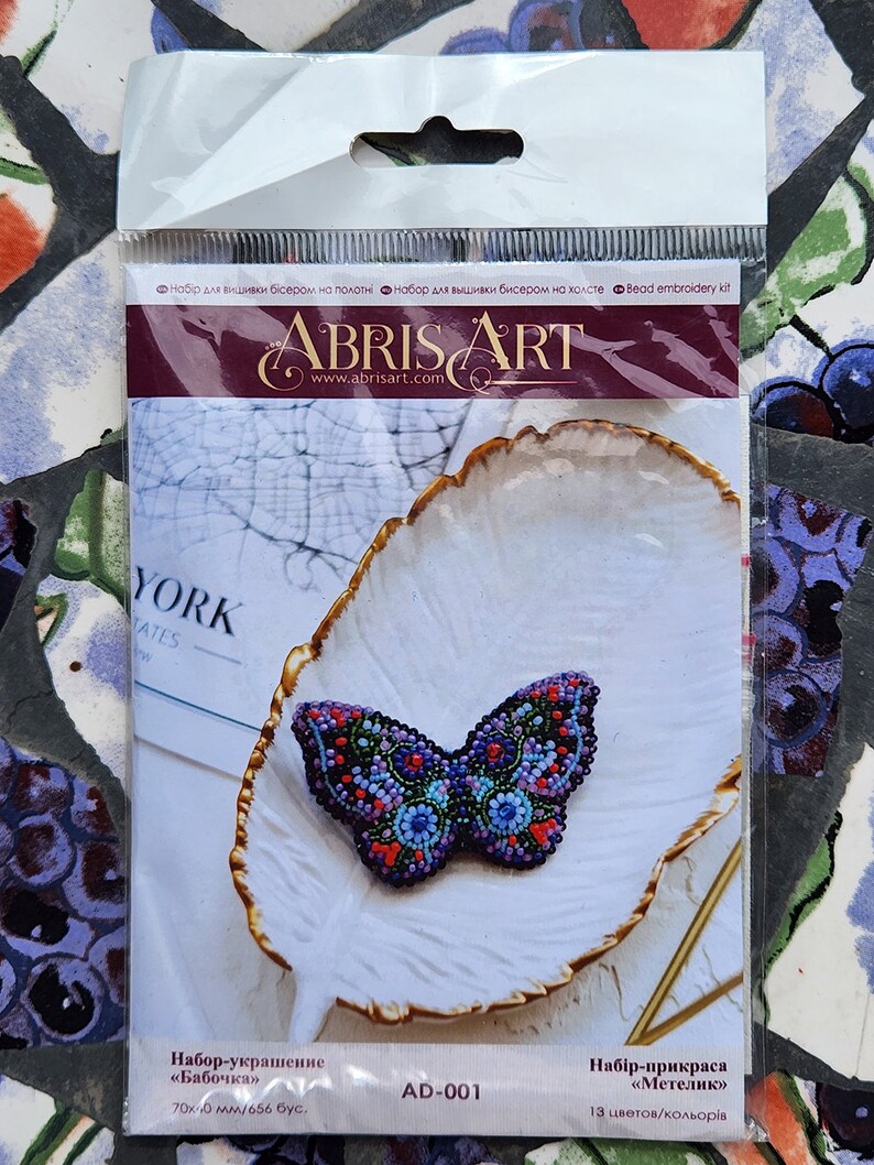 May include: A bead embroidery kit featuring a butterfly design. The butterfly is made of colorful beads and is approximately 70mm x 40mm. The kit includes 656 beads and is labeled "AD-001".