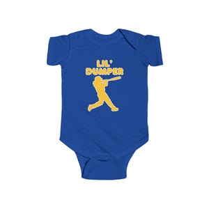 May include: A royal blue baby bodysuit with a yellow graphic of a baseball player swinging a bat. The text "LIL' DUMPER" is above the graphic in yellow. The bodysuit is made of soft fabric.