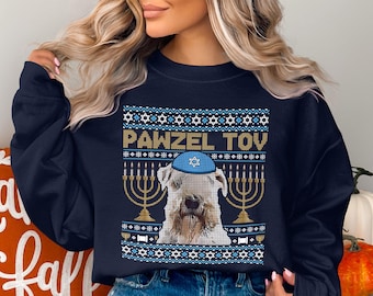 May include: Navy blue sweatshirt with a festive design. The design features a dog wearing a blue yarmulke, menorahs, and the text "PAWZEL TOV" in gold. The design includes blue and white Star of David patterns.