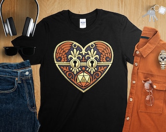 May include: Black t-shirt with a gold, ornate heart design featuring a keyhole and a 20-sided die. The heart is surrounded by intricate floral details.