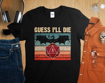 May include: Black t-shirt featuring a vintage-style graphic of a dragon and a red twenty-sided die with the number one showing. The text "GUESS I'LL DIE" is printed above the graphic.