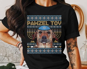 May include: Black t-shirt featuring a dog wearing a blue yarmulke, with the text "PAWZEL TOV" above the dog. The design includes menorahs and Star of David patterns, creating a festive holiday theme.