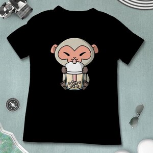 May include: Black t-shirt with a cartoon monkey wearing a brown hat and drinking a boba tea.
