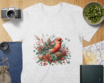 May include: A white t-shirt with a colorful illustration of a bird perched on a branch with red berries, pine cones, and flowers. The bird has a red breast and blue wings.