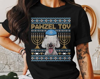 May include: Black t-shirt with a festive design featuring a dog wearing a blue yarmulke, menorahs, and the text "PAWZEL TOV" in gold. The design has a blue and white pattern.