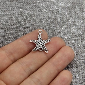 Puede incluir: Encanto de estrella de mar de metal plateado con un diseño texturizado detallado. El encanto tiene un bucle en la parte superior para sujetarlo a joyas u otras manualidades.