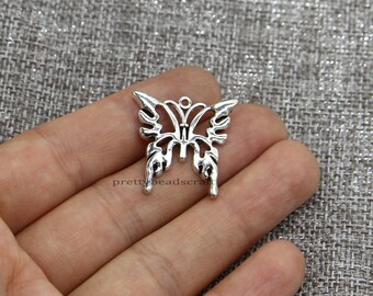 Pode incluir: Encanto de borboleta de metal prateado com um design intrincado. O encanto tem um laço na parte superior para prender a joias ou outras manualidades.
