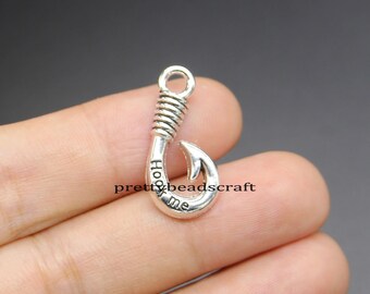 May include: Silver-toned metal charm shaped like a fishing hook with the words "Hook Me" engraved on the hook.