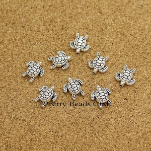 May include: Eight silver turtle charms with detailed shell designs. These charms are perfect for jewellery making, scrapbooking, and other craft projects.