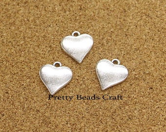 May include: Three silver heart-shaped charms with a slightly textured finish. The charms have a loop at the top for attaching to jewelry or other crafts.