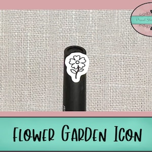 Op de afbeelding: Een zwart-witte sticker van een eenvoudige bloem met vijf bloemblaadjes en een stengel. De sticker zit op een zwarte marker, die op een wit, getextureerd oppervlak ligt. De tekst "FLOWER GARDEN ICON" staat onderaan de afbeelding.