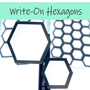 Op de afbeelding: Twee witte zeshoekige stickers met een zwarte rand en een zwart-wit honingraatpatroon op de achtergrond. De tekst "Write-On Hexagons" staat bovenaan de afbeelding.