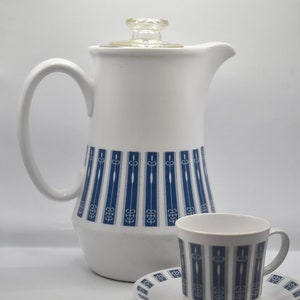 以下が含まれることがあります： 青と白の幾何学模様が施された白いセラミック製のコーヒーポット。ポットにはガラス製の蓋と、それに合わせたカップとソーサーが付いています。